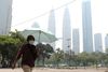 Indbyggere i Kuala Lumpur har iført sig masker for at beskytte sig mod røgen. I baggrunden Twin Towers, der er indhyllet i røgen. Foto: Lim Huey Teng/Reuters