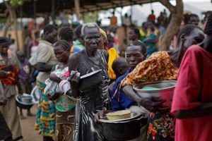 Flygtninge fra Sydsudan står i kø i en flygtningelejr i Uganda, hvor over én mio. er taget til. Arkivfoto: Ben Curtis