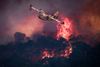 TOPSHOT - A French Civil Security Canadair CL-415 aircraft flies past flames burning a forest surrounding Cotignac, southeastern France on July 23, 2026 during a wildfire. The fierce fire that struck the Var region and has burned across 2, 500 hectares "remains stable" on July 23 morning, announced the Prefect of the Var, Simon Babre, who has authorised the 400 people who were evacuated to return to their homes to "enable the damage to be assessed". Some 650 firefighters were still deployed in the Gros Bessillon area, a mid-altitude mountain range in central Var, one of France's most forested departments. (Photo by Thibaud MORITZ / AFP)