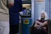 En pensionist sidder foran en hæveautomat i Grækenland, hvor folk står i kø for at hæve penge.
