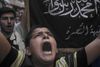 En syrisk dreng råber slogans vendt mod regimet foran et banner fra den bevæbnede islamistiske Nusrafront.