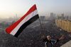En egypter holder det nationale flag, mens militærhelikoptere hænger i luften over ham og den enorme menneskemængde, som indtog Tahrir-pladsen i Kairo på treåret for Det Arabiske Forår, som væltede landets mangeårige præsident, Hosni Mubarak. Nu – i 10-året for revolutionen – har der til gengæld været stille på pladsen. Præsident Abdel Fattah al-Sisi har et jerngreb om magten og slår hårdt ned på politiske kritikere og ytringsfriheden. Foto: Amr Nabil/AP