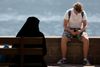 En kvinde med niqab sidder i solen i Zell am See. Selv om Østrig har fået et burkaforbud, løber hun ikke den store risiko for at få en bøde. Foto: ALEX HALADA/AFP