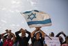 Asylsøgere i Israel har de seneste måneder protesteret mod udsendelser til centre i Afrika. Her holder demonstranter bl.a. et israelsk flag ved en protestaktion ved Saharonim-fængslet i Negev-ørkenen i Israel. Foto: Ilia Yefimovich/dpa/AP Images
