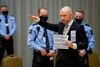 Terroristen Anders Behring Breivik ankom tirsdag formiddag til den improviserede retssal ved fængslet i Skien med løftet arm og skriftligt budskab rede. Foto: Ole Berg-Rusten/NTB