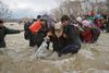 Migranter og flygtninge har i marts 2016 forladt en overfyldt lejr og forsøger at krydse en flod nord for Idomeni i Grækenland. Nu får migranterne også en plads i FN. Det sker på det stort anlagt topmøde, som finder sted mandag i New York. Arkivfoto: Vadim Ghirda