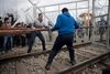 En gruppe flygtninge og migranter forsøgte mandag at bryde gennem grænseporten fra Grækenland til Makedonien, hvilket resulterede i, at makedonsk politi svarede igen med tåregas. Foto: Petros Giannakouris/AP