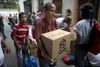Store dele af befolkningen i Venezuela har svært ved at klare sig i det kaotiske land. Her henter en kvinde i Caracas en af regeringens hjælpepakker med basisfødevarerne bønner, ris, tun og mælkepulver. Foto: AP