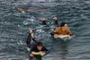 En haj svømmer tæt på surfere i Bells Beach i den australske delstat Victoria. Søndag blev en surfer dræbt af en haj i delstaten New South Wales. Foto: Graham Blade/Reuters