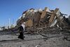 En palæstinensisk kvinde i Gaza by går forbi et højhusbyggeri, som natten til onsdag blev jævnet med jorden af israelske luftangreb. Foto: Mohammed Abed/AFP