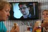 Transitpassagerer i Moskvas internationale lufthavn spiser, mens whistlebloweren Edward Snowden optræder på tv i baggrunden. Snowden befinder sig stadig et eller andet sted i lufthavnen. Foto: Sergej Grits/AP