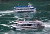 Den amerikanske turistbåd 'Maid of the Mist' glider forbi den canadiske 'Hornblower'. Den markante forskel i antallet af passagerer har gjort billedet til symbol på, hvordan den amerikanske coronaindsats adskiller sig fra den canadiske. Foto: REUTERS/Carlos Osorio