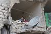 Billedet er fra Aleppo i feburar 2016 og viser børn, der kigger ud af en bygning gennem et hul lavet af en bombe. Foto: Alexander Kots/AP