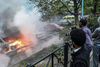 Urolighederne har bredt sig til en række Stockholm-forstæder. Her tager tilskuere billeder af en række biler, der er blevet sat i brand i Rinkeby. Foto: Frederik Sandberg/AP