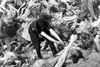 En kvindelig tysk vagt rydder op i en ligdynge i kz-lejren Bergen-Belsen efter lejrens befrielse i 1945. I de seneste 65 år er mange stillet til regnskab for deres gerninger, men der er endnu få tilbage, der aldrig er blevet retsforfulgt. Foto: AP