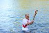 Den japanske olympiske fakkelbærer Katsumi Nishimizu med den olympiske ild efter at have svømmet i en flod i Usuki i Oika-præfekturet. Foto: Handout/Tokyo 2020/AFP