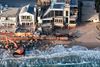 DANA POINT, CALIFORNIA - SEPTEMBER 14: In an aerial view, a Pacific Ocean wave washes up near a worker using heavy machinery to protect damaged beachfront homes with boulders on September 14, 2026, in Dana Point, California. Heavy surf generated by Hurricane Marie offshore over Labor Day weekend, amid a record-breaking ocean heatwave and an emerging El Niño, left approximately ten properties in the area to be deemed uninhabitable and prompted Dana Point to declare a local emergency over coastal erosion. Mario Tama/Getty Images/AFP (Photo by MARIO TAMA / GETTY IMAGES NORTH AMERICA / Getty Images via AFP)