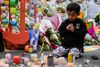 Et barn sidder mellem blomster og lys - de sidste hilsener til ofrene for terrorangrebene i Christchurch i New Zealand fredag. I alt 50 mennesker blev dræbt. Foto: Anthony Wallace/AFP.