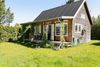 Kolonihavehuset i beskeden sydstatsstil med overdækket veranda har tagpap på taget og ydervægge af imprægneret fyrretræ, der skal lakeres i en lavendelblå tone. Hulrummet under verandagulvet bruges til opbevaring af brænde.