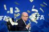 Pengesedlerne dalede ned over den afgående præsident for Fifa Sepp Blatter, da den engelske komiker Simon Brodkin på et pressemøde i juli 2015 ikoniserede de tiltagende korruptionsanklager mod Blatter ved at overdynge schweizeren med penge. Foto: Ennio Leanza/Keystone/AP