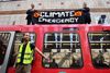 To aktivister med et banner var onsdag formiddag kravlet op på taget af et tog ved Canary Wharf station, mens en tredje har limet sig selv fast til toget. Foto: Daniel Leal-Olivas/AFP