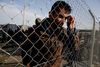 Hertil og ikke længere. Ved hegnet på grænsen mellem Grækenland og Makedonien venter en afghansk migrant på at blive sat på en bus til Athen. Foto: Petros Giannakouris/AP