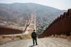Den amerikanske grænsebetjent Fabian Carajal står på den nyanlagte grusvej på grænsen til Mexico. hvor konstruktionsarbejdere er i gang med at opføre de næste sektioner af Trumps mur. Den 36-årige tidligere marinesoldat mødte præsidenten, da Trump sidste år besøgte grænseregionen. Carajal har et billede af besøget hængende hjemme på sin væg. Foto: Ed Kashi