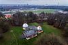 I Ole Rømer Observatoriet plejer man at kigge nedefra og op ud i verdensrummet. Her gør vi det så lidt modsat. Vi ser oberservatoriet oppefra og ned. Det gule hus med det røde tag er observatorievillaen, det hvide bagved er stalde. Ellers ses travbanen, stadion og Aarhus. Foto: Casper Dalhoff