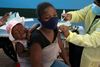En mor med sit barn bliver vaccineret i Diepsloot Township nær Johannesburg i slutningen af oktober, da Sydafrika besluttede at påbegynde vaccination af de 12-17-årige. Nye data fra landets sundhedsmyndigheder viser, at børn og unge i langt højere grad bliver indlagt. Foto: Denis Farrell/AP