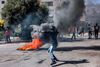 A Palestinian protester hurls back a tear gas canister with a sling during clashes with Israeli forces following a rally in solidarity with Gaza by supporters of the Fatah and Hamas movements, in the city of Hebron in the occupied West Bank on October 13, 2023. AFP correspondents and a security official reported clashes after rallies in solidarity with war-battered Gaza in Ramallah, Nablus, Tulkarm, Hebron and other cities and towns, with the Palestinian Red Crescent reporting dozens wounded across the West Bank, some critically. (Photo by HAZEM BADER / AFP)